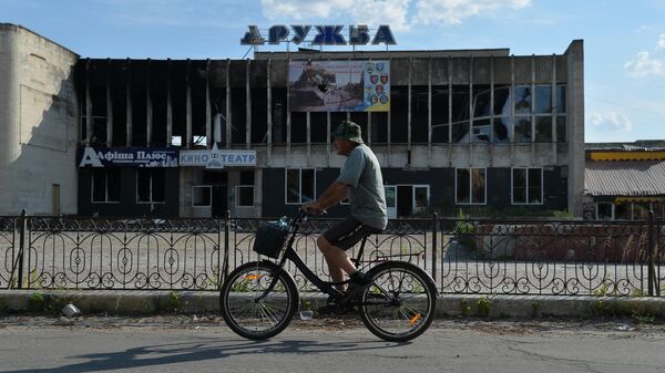 Велосипедист едет мимо разрушенного здания кинотеатра Дружба в Лисичанске
