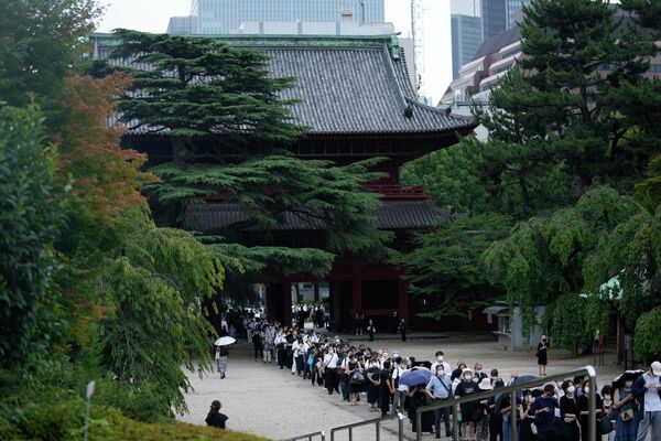 Люди стоят в очереди перед молитвой, чтобы отдать дань уважения бывшему премьер-министру Японии Синдзо Абэ в храме Дзодзёдзи, Токио