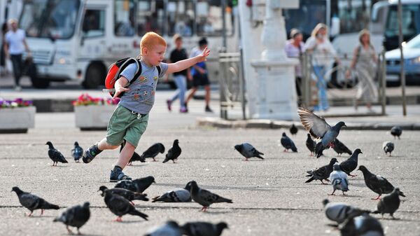 Мальчик гоняет голубей на Сусанинской площади в Костроме