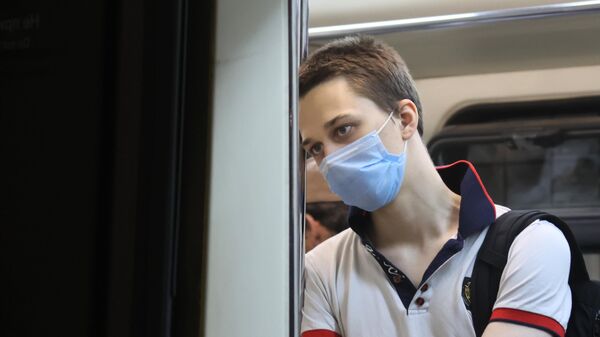 Молодой человек в защитной маске в вагоне поезда Московского метрополитена