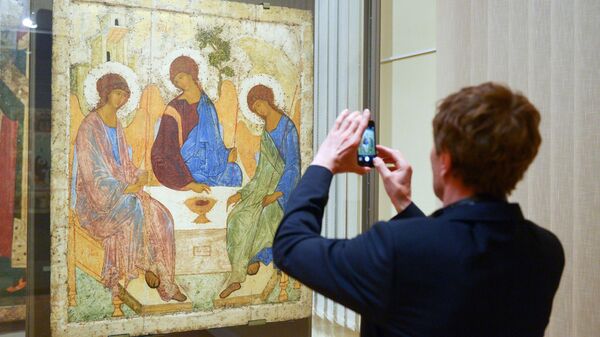 Молодой человек фотографирует икону художника Андрея Рублева Троица в Третьяковской галерее