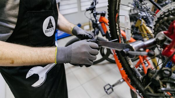 Мастер производит ремонт колеса велосипеда в веломастерской Высота в Иванове