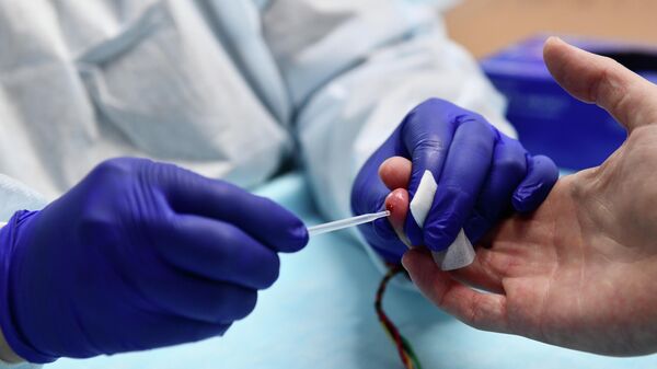 Медицинский работник производит экспресс-анализ крови в мобильном пункте анонимного экспресс-тестирования на ВИЧ