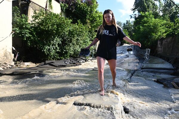 Девушка идет по пострадавшему из-за сильного наводнения Виноградному переулку в Соч