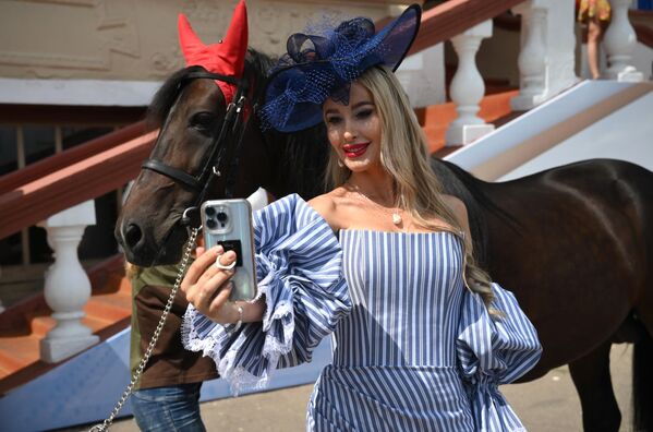 Девушка фотографируется с лошадью перед началом скачек в честь 20-летия конного завода Донской на Центральном Московском ипподроме