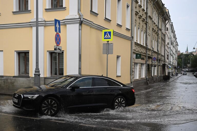 Автомобиль едет по лужам на улице Ленивка в Москве