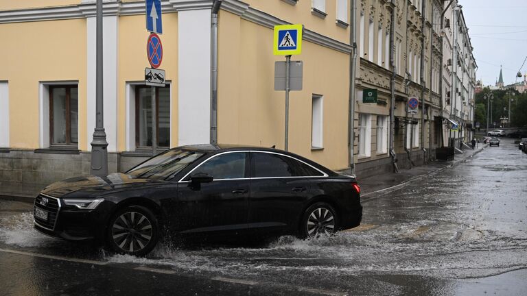 Автомобиль едет по лужам на улице Ленивка в Москве