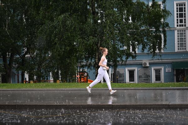 Женщина переходит улицу по лужам в Москве