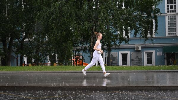 Женщина переходит улицу по лужам в Москве
