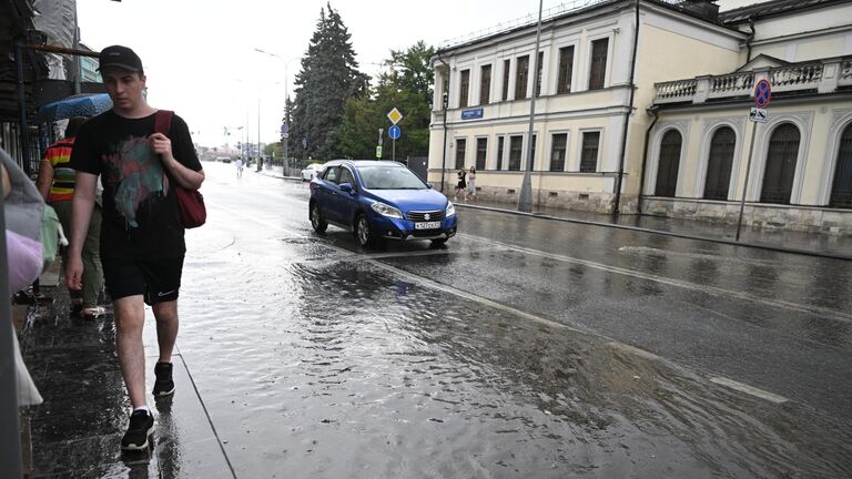 Мужчина идет по лужам на улице Волхонка в Москве