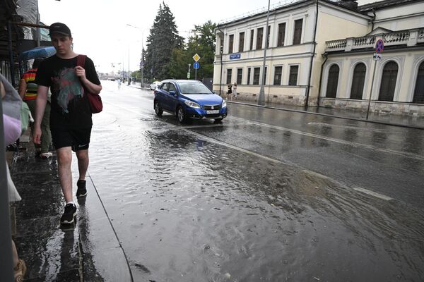 Мужчина идет по лужам на улице Волхонка в Москве
