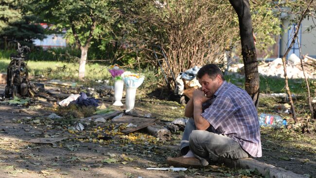 Мужчина на месте гибели родственника в Горловке, подвергшейся ракетно-минометному обстрелу.