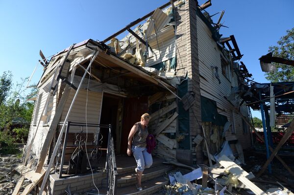Местная жительница выходит из дома, пострадавшего во время ракетно-минометного обстрела Горловки в Донецкой области.