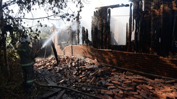 Пожарный работает на месте возгорания в доме, пострадавшем во время ракетно-минометного обстрела Горловки в Донецкой области.