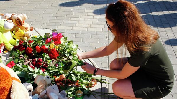 Девушка возлагает цветы к памятнику Аллея Ангелов в парке Победы Калининского района Донецка во время акции в память о детях, погибших в ходе конфликта на юго-востоке Украины