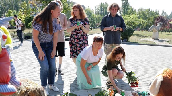 Люди возлагают цветы и ставят свечи к памятнику Аллея Ангелов в парке Победы Калининского района Донецка во время акции в память о детях, погибших в ходе конфликта на юго-востоке Украины