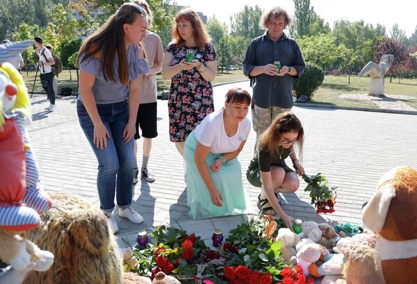 Люди возлагают цветы и ставят свечи к памятнику Аллея Ангелов в парке Победы Калининского района Донецка во время акции в память о детях, погибших в ходе конфликта на юго-востоке Украины