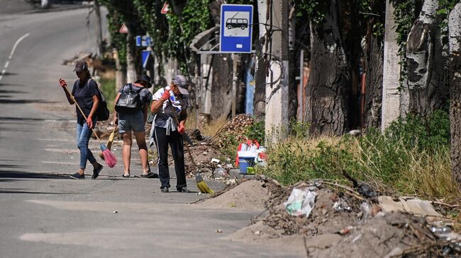 Женщины подметают дорогу в Мариуполе