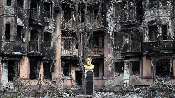 Памятник писателю Владимиру Короленко у разрушенного жилого дома в Мариуполе