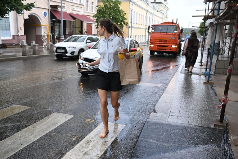 Женщина босиком переходит улицу по лужам в Москве