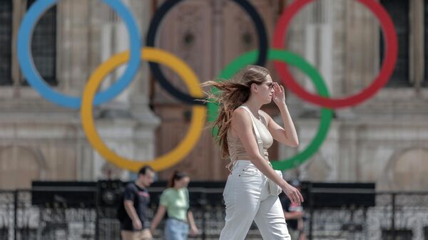 Девушка проходит мимо олимпийских колец возле мэрии в Париже