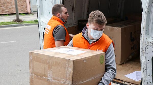 Волонтеры выгружают промаркированные коробки с гуманитарной помощью