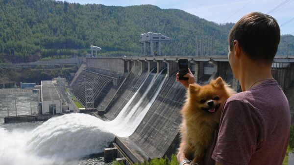 Мужчина снимает на мобильный телефон сброс воды на Красноярской ГЭС
