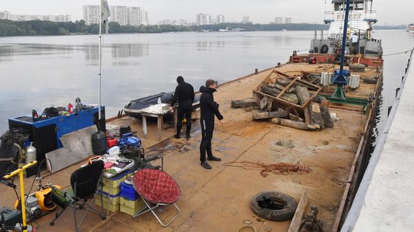 Водолазы на барже с собранным мусором во время работ по очистке дна причалов Северного речного вокзала на берегу Химкинского водохранилища в Москве