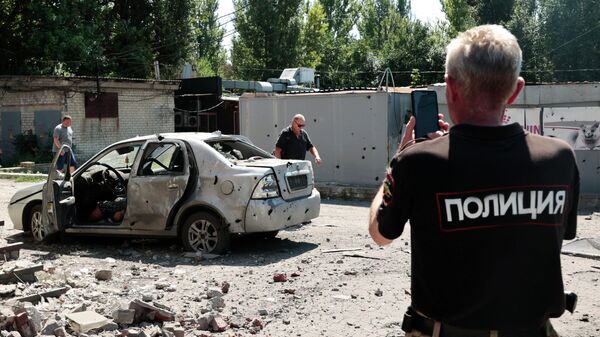 Сотрудник полиции у автомобиля после обстрела ВСУ в Кировском районе Донецка