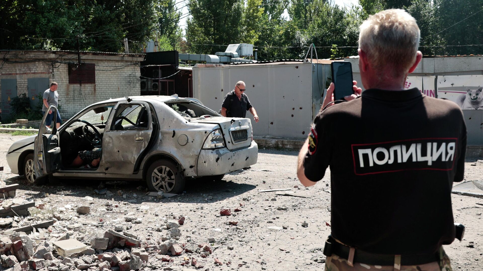 Сотрудник полиции у автомобиля после обстрела ВСУ в Кировском районе Донецка - РИА Новости, 1920, 29.08.2022