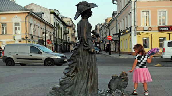 Девочка у памятника Дама с собачкой на Петровской набережной в Астрахани