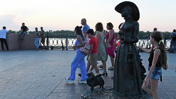Туристы у памятника Дама с собачкой на Петровской набережной в Астрахани