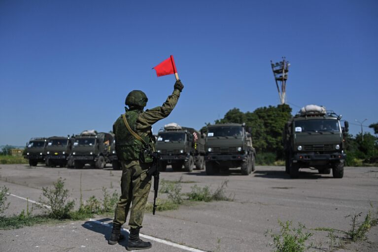 Военнослужащий подает сигналы флажком для проезда военной техники на территории аэропорта Мариуполя