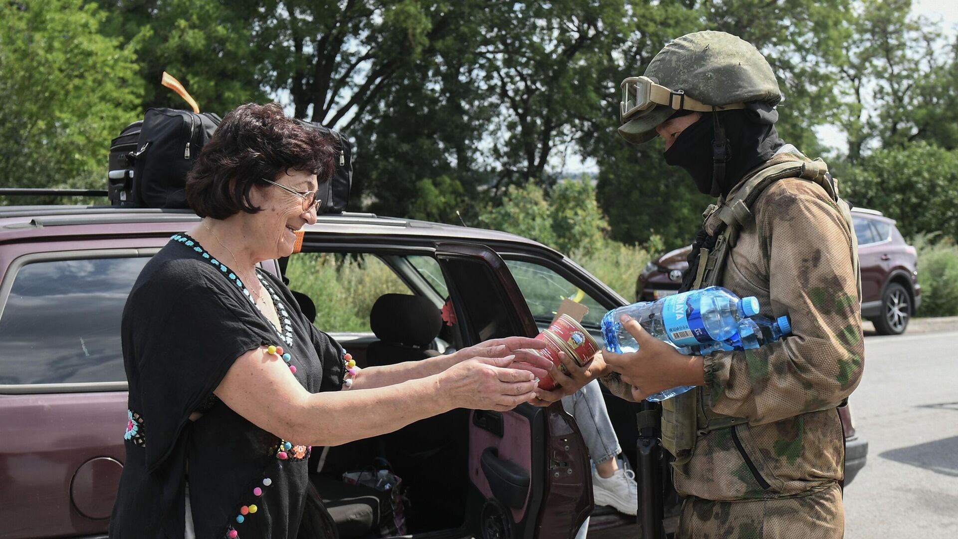 Военнослужащий РФ передает воду и консервы женщине стоящей в автомобильной пробке возле КПП Васильевка на границе Запорожской области - РИА Новости, 1920, 02.04.2023