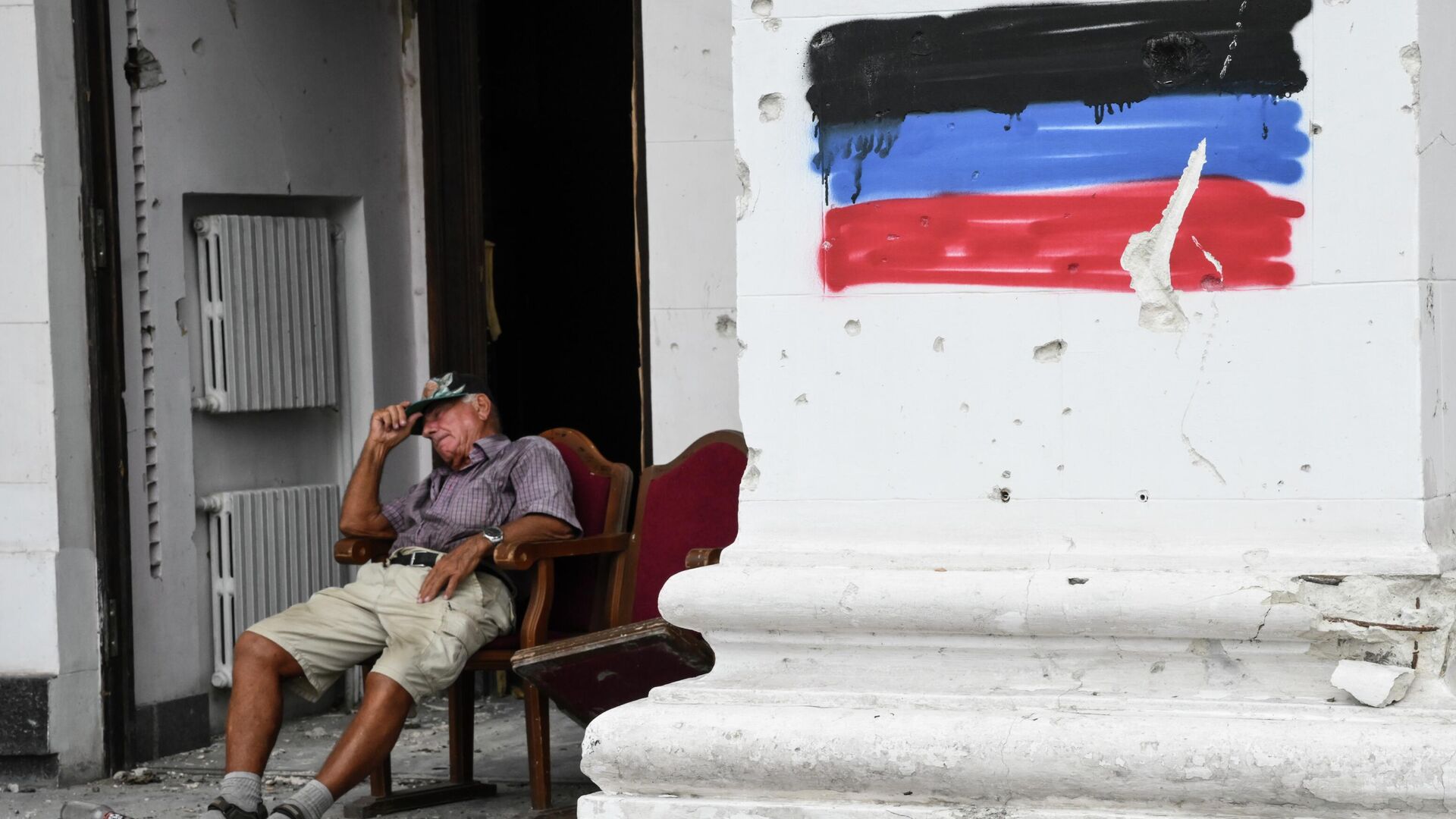 Мужчина отдыхает у входа в здание Мариупольского драматического театра - РИА Новости, 1920, 23.08.2022