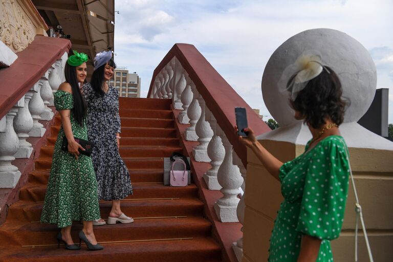 Посетительницы фотографируются на Центральном Московском ипподроме перед началом скачек Праздника чистокровного коннозаводства