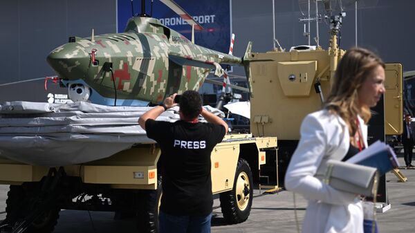 Представитель СМИ фотографирует беспилотник БАС-750 на выставке в центре Патриот