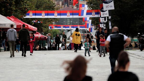 Люди идут по улице, украшенной  флагами Сербии, в северной части  Косово