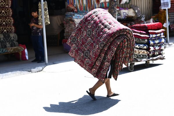 Мужчина несет матрасы на рынке в Ташкенте