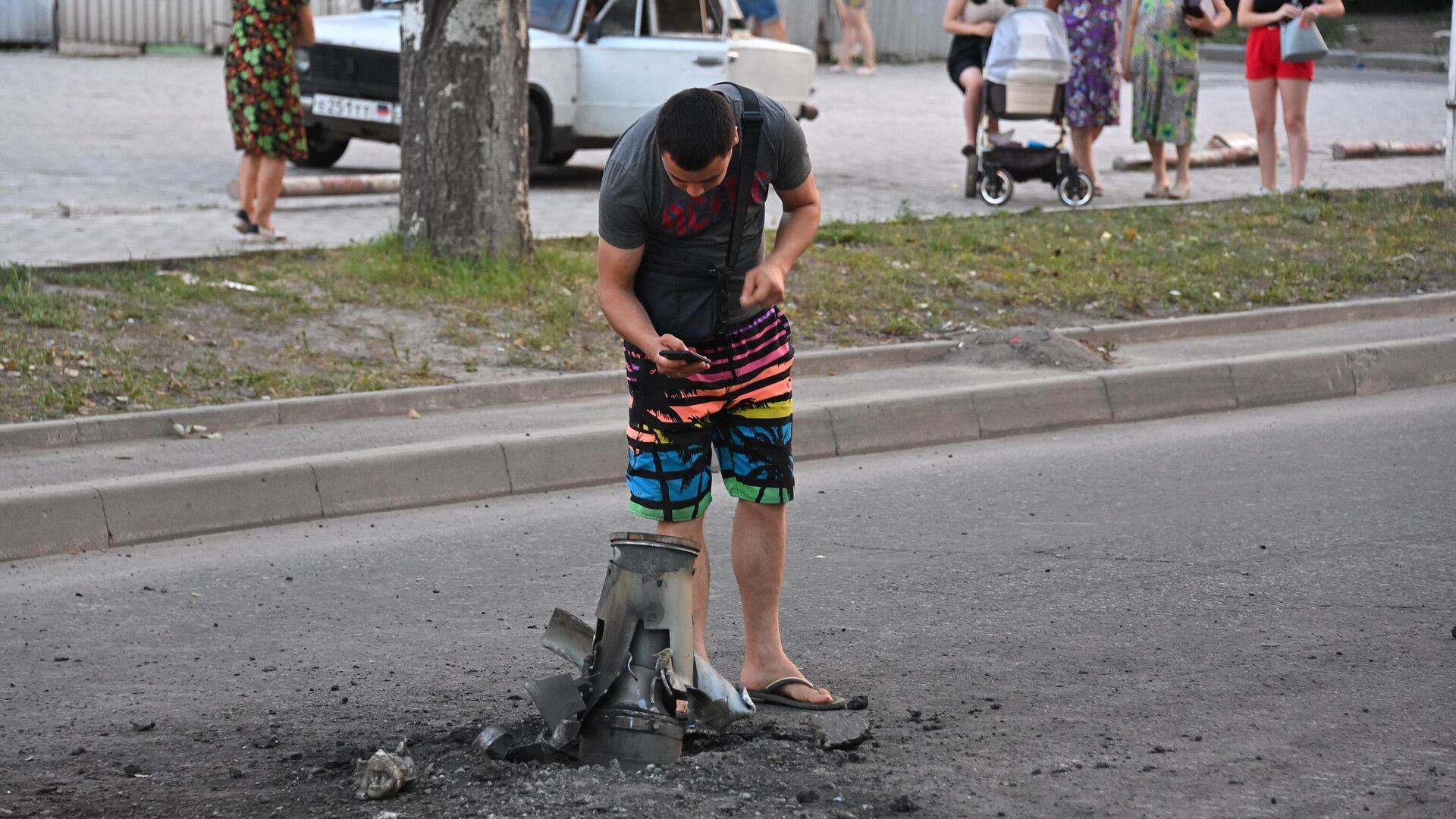 Жители города около неразорвавшегося боеприпаса на месте обстрела Ленинского района Донецка - РИА Новости, 1920, 01.09.2022