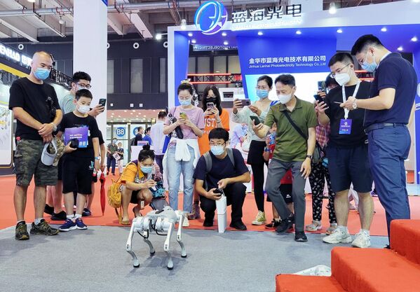 Посетители возле робота-собаки на Всемирной конференции робототехники в Пекине
