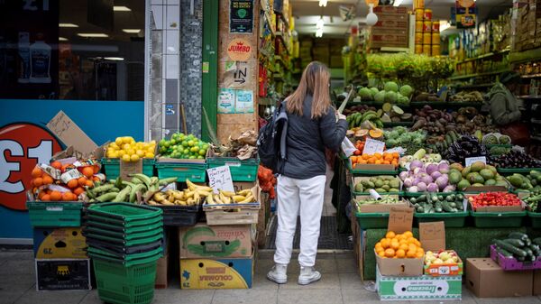 Покупательница у лавки фруктов и овощей в Лондоне