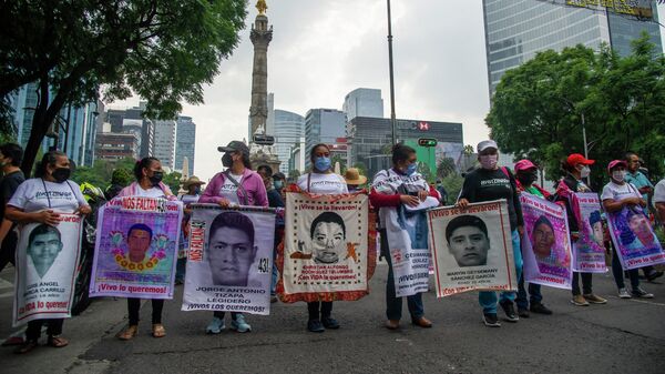 Родственники с портретами пропавших без вести студентов во время акции протеста в Мехико