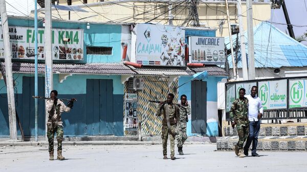 Сотрудники службы безопасности патрулируют место взрывов в Могадишо, Сомали