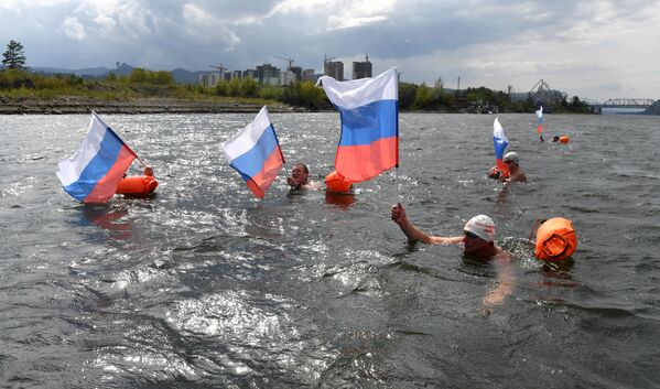 Участники клуба зимнего плавания Енисейские моржи во время заплыва в холодной воде в честь Дня государственного флага РФ в Красноярске