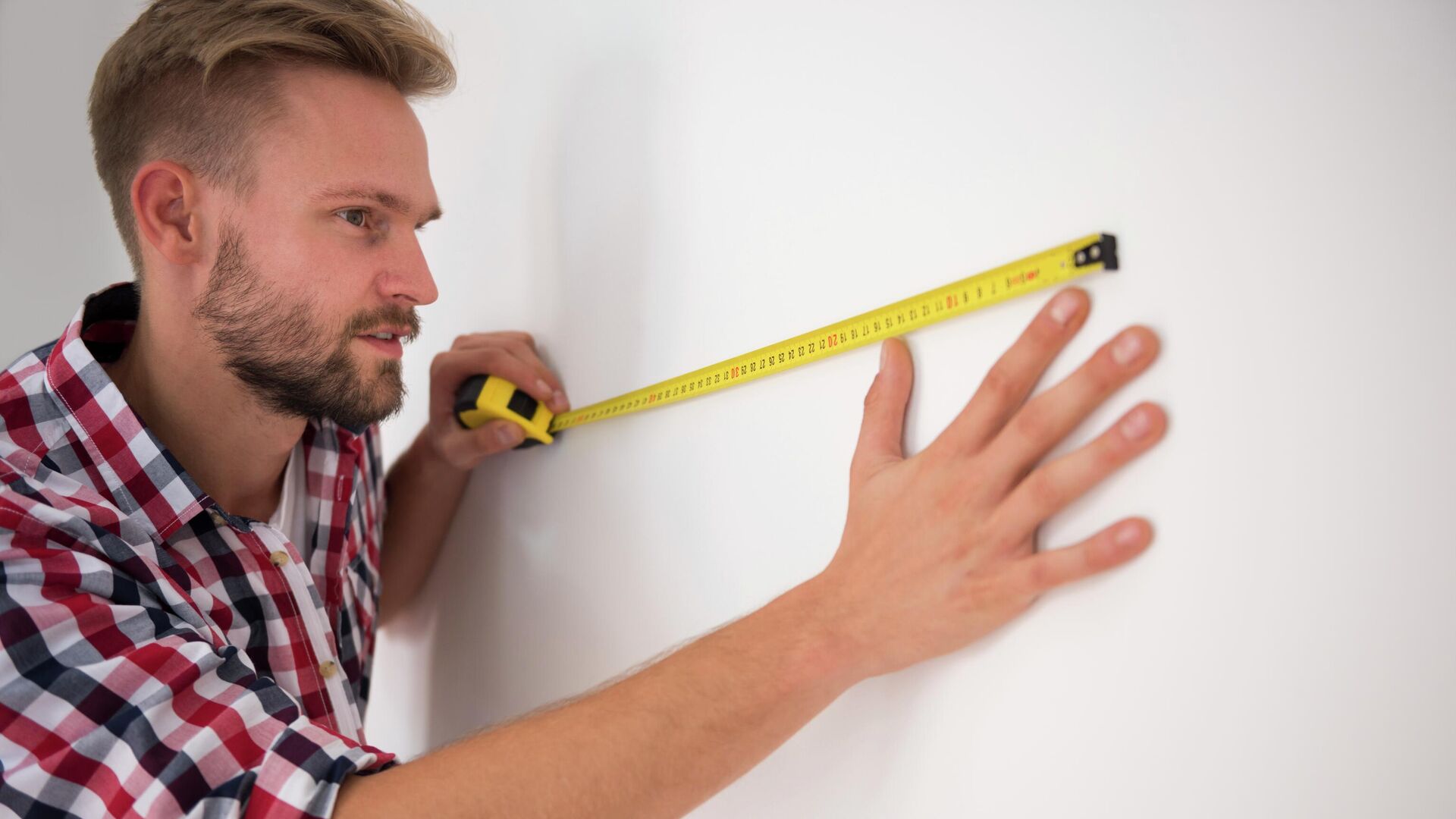 Мужчина измеряет стену рулеткой - РИА Новости, 1920, 20.11.2025