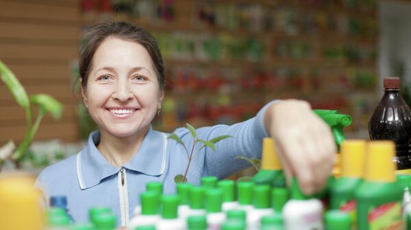 Женщина выбирает удобрения в цветочном магазине
