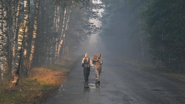 Женщины идут с иконами по дороге в Рязанской области через лес, пострадавший от пожара