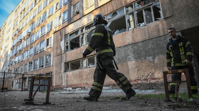 Сотрудники пожарной охраны возле здания Донецкого национального технического университета, поврежденного в результате обстрела ВСУ