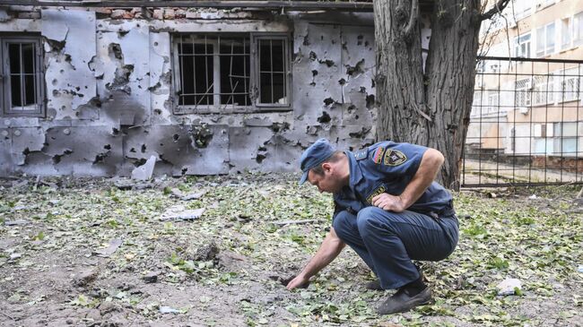 Сотрудник МЧС ДНР возле здания, поврежденного в результате обстрела ВСУ